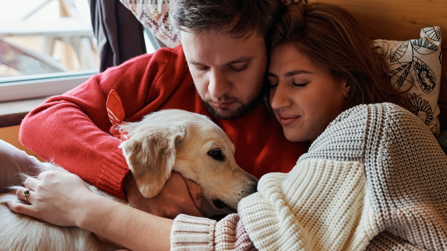 man and woman cuddling a golden retriever